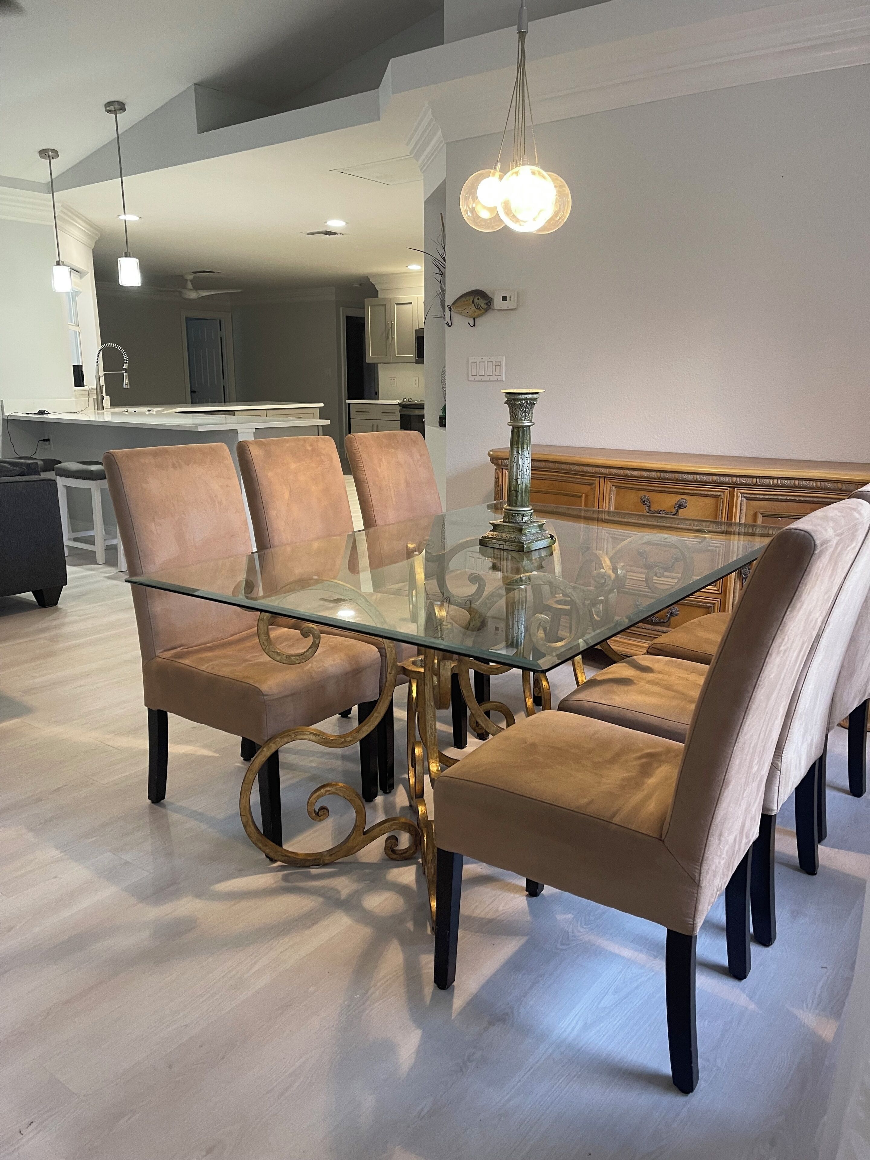 A dining area with a glass-top table, four cushioned chairs, and a decorative centerpiece.