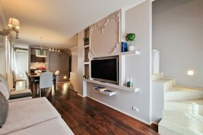 Un soggiorno moderno con una TV a schermo piatto, mensole a muro e una scala.