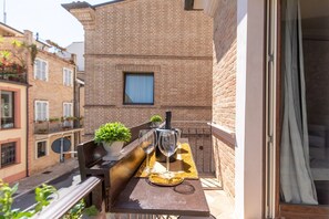 Un balcone con un tavolo apparecchiato per due persone, una pianta in vaso e una bottiglia di champagne.