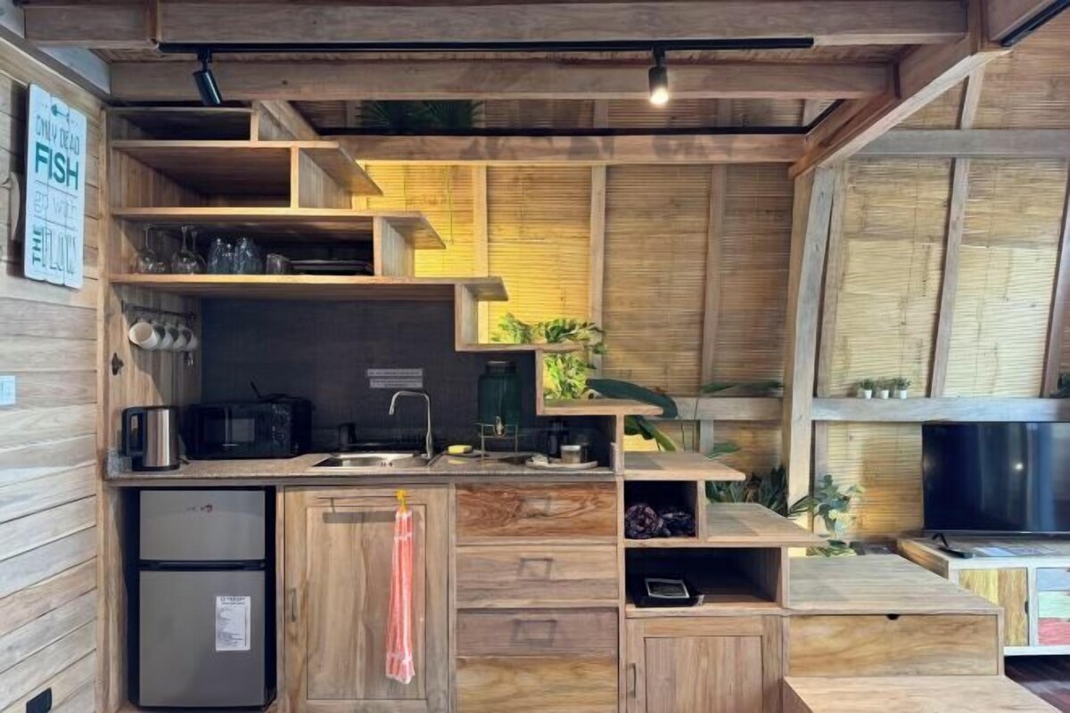 Une cuisine compacte avec des meubles en bois, un petit réfrigérateur et un four à micro-ondes.