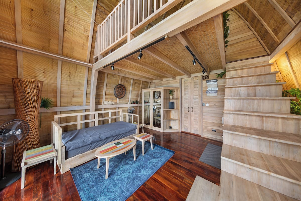 Un intérieur en bois avec un lit en mezzanine, une table à manger et un escalier.