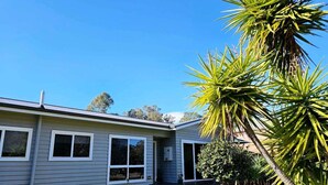 A single-story house with a grey exterior, a front porch, and a small front yard with a palm tree. - Quantrill Avenure Retreat (Benalla)