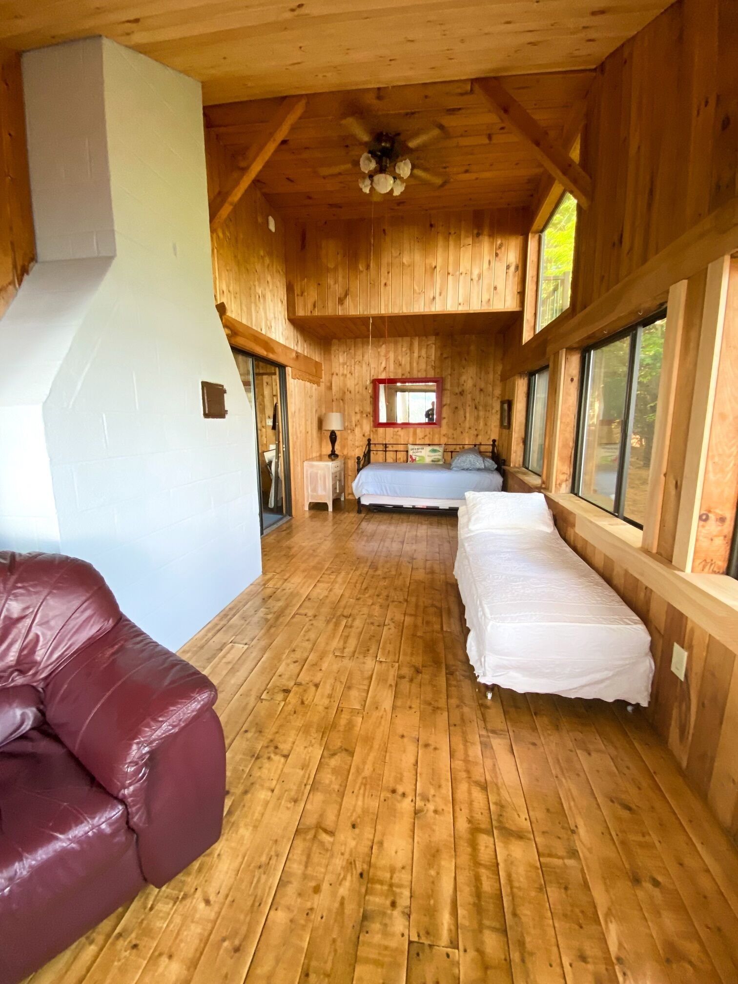 A cabin with a wooden interior, a bed, a nightstand, and a window.