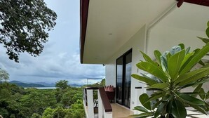 Une maison moderne dotée d’un balcon donnant sur un paysage luxuriant.