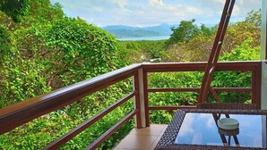 Un balcon donnant sur une végétation luxuriante et un lac.