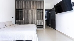 Un dormitorio con cama, armario y televisor montado en la pared.