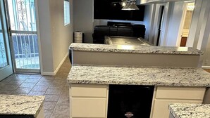 Una cocina moderna con encimeras de granito, lavavajillas integrado y refrigerador negro.
