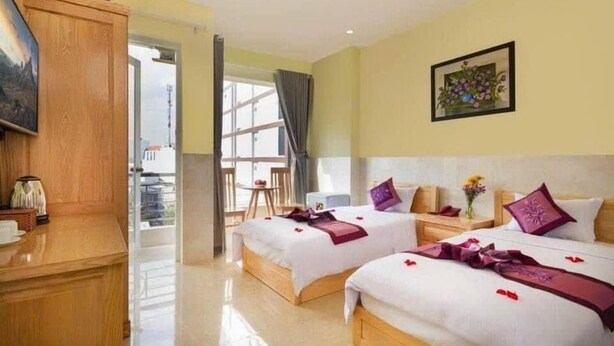 A hotel room with two beds, a wooden desk, a painting, and a window with curtains. - Dream Hotel (Nha Trang)