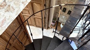 Un escalier en colimaçon, avec un mur en pierre et une porte en bois en arrière-plan.