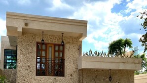 Une maison à deux étages avec une façade en pierre, un balcon orné d’une balustrade en fer forgé et un vélo garé devant.