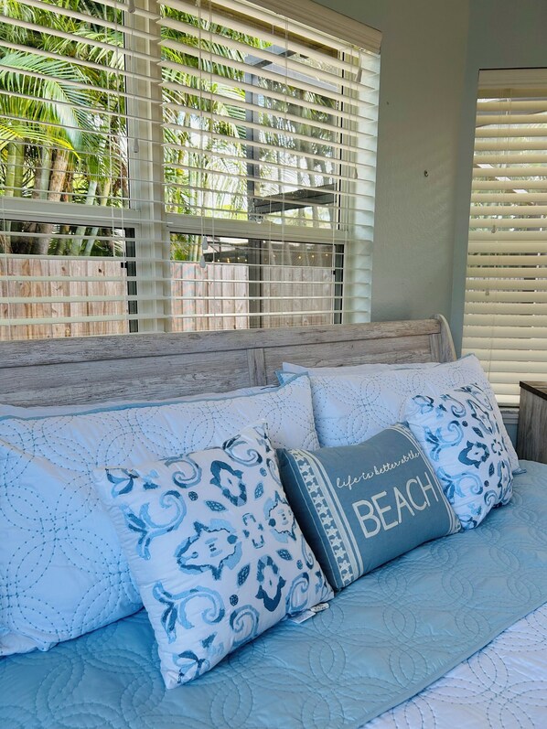 A bedroom with a bed, pillows, and a window with blinds.