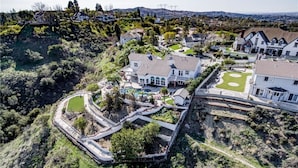 An aerial view of a residential area with houses, a winding road, and a large garden. - Luxury Hill Villa with Spectacular View (Anaheim)