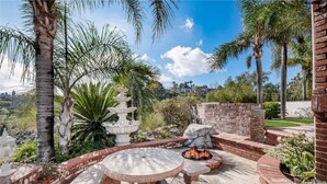 A patio area with a fire pit, seating, and a decorative stone structure. - Luxury Hill Villa with Spectacular View (Anaheim)