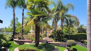 A landscaped garden with palm trees, a fountain, and a well-maintained lawn. - Luxury Hill Villa with Spectacular View (Anaheim)