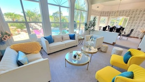 A spacious living room with a large window, a sofa, two yellow armchairs, and a coffee table. - Luxury Hill Villa with Spectacular View (Anaheim)