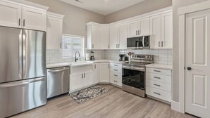 A modern kitchen with white cabinetry, stainless steel appliances, and a tiled backsplash. - New! Main Street Retreat | BBQ | Pac-Man (Lehi)
