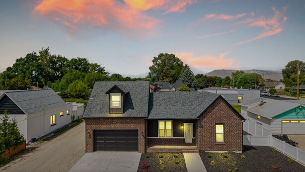 A modern two-story house with a garage, surrounded by a landscaped garden and a driveway. - New! Main Street Retreat | BBQ | Pac-Man (Lehi)