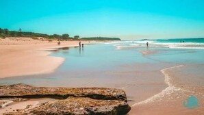 A beach with clear skies, calm waters, and rocky outcrops. - Caves Cottage - gorgeous 180 degree ocean views (Caves Beach)