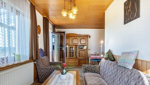 A living room with a sofa, a coffee table, a cabinet, and a window with curtains. - Apartment 'Haus Gisela Berger' with Shared Terrace, Shared Garden and Balcony (Dachsberg)