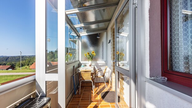 A balcony with a table, chairs, and a vase of sunflowers. - Apartment 'Haus Gisela Berger' with Shared Terrace, Shared Garden and Balcony (Dachsberg)