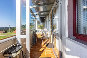 A balcony with a table, chairs, and a vase of sunflowers.