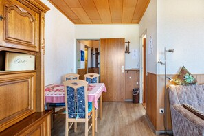 A wooden interior with a dining table, chairs, a sofa, and a built-in cabinet.