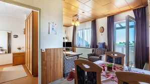 A cozy room with a dining table, chairs, a sofa, and a view of the outdoors. - Apartment 'Haus Gisela Berger' with Shared Terrace, Shared Garden and Balcony (Dachsberg)