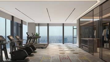 A modern gym with treadmills, a city view, and a glass-enclosed changing room.