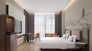 A modern hotel room with a large bed, a desk, a chair, and a television.