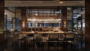 A modern bar area with a central bar, multiple shelves of bottles, and a seating area with tables and chairs.