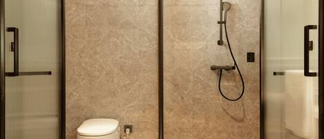 A modern bathroom with a toilet, a shower, and a glass partition.