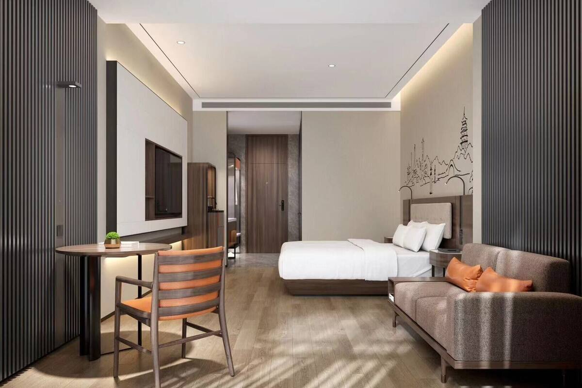 Een moderne hotelkamer met een bed, een bank, een bureau en een televisie.