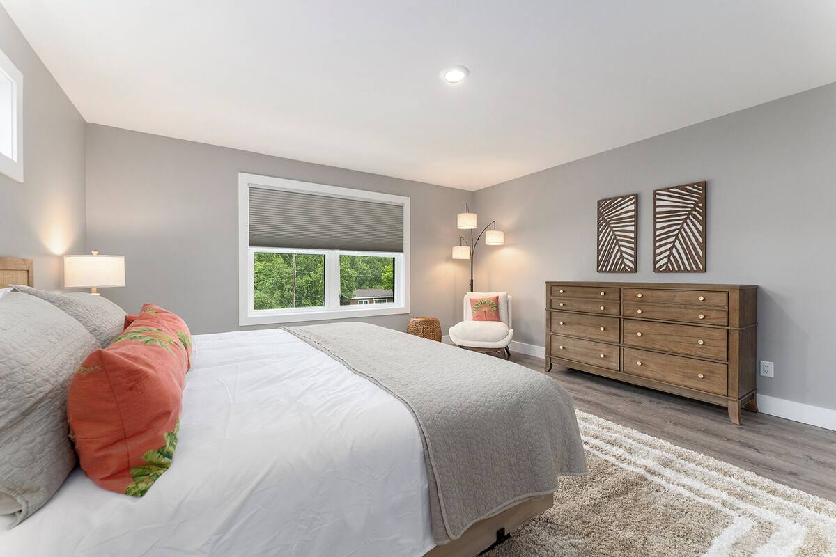 Un dormitorio con cama, cómoda, silla y ventana con persianas.