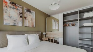A modern hotel room with a large bed, a desk, and a walk-in closet.