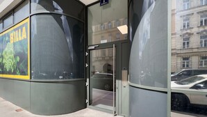 A building entrance with a glass door, a sign reading "Hardison," and a large advertisement for "BILLA" on the left.