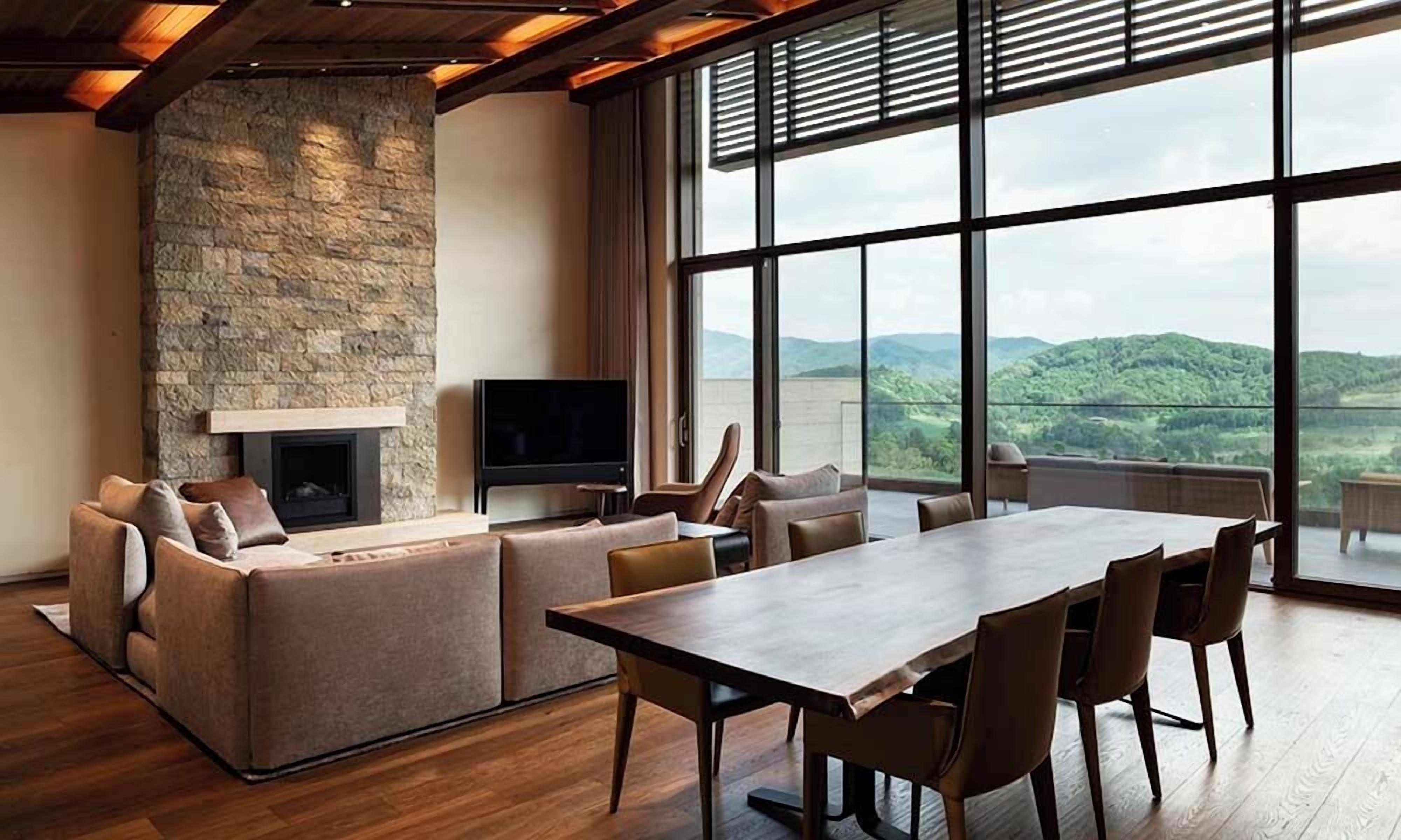 A spacious living area with a stone fireplace, a flat-screen TV, and a large dining table with chairs.