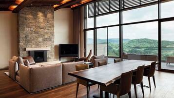 A spacious living area with a stone fireplace, a flat-screen TV, and a large dining table with chairs.