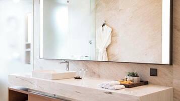 A modern bathroom with a large mirror, a marble countertop, a sink, and a towel rack.