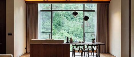 Una cocina moderna con un amplio ventanal, techo de madera y un comedor con sillas.