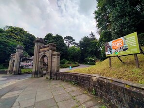 Enter Williamson Park through a historic stone archway, surrounded by lush greenery and leading to a variety of amenities.