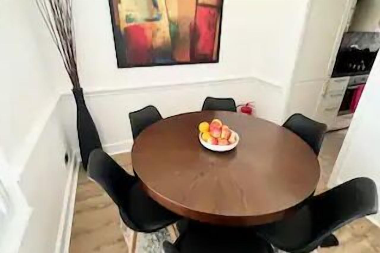 A dining area with a round table, black chairs, and a bowl of fruit.