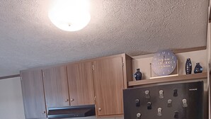 Eine Küche mit Holzausstattung, einem schwarzen Kühlschrank, einem Herd und einer Mikrowelle.