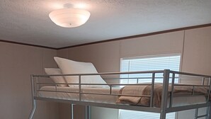 Ein Schlafraum mit Etagenbetten, einem Fenster, Holzboden und einer Deckenleuchte.