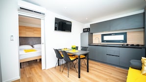 Eine kompakte, moderne Wohnung mit Küchenzeile, Essbereich und Bett.
