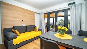 Ein modernes Wohnzimmer mit Sofa, Esstisch und Blick ins Freie.