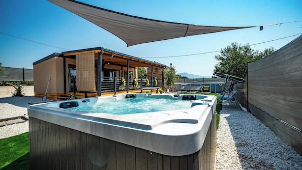 Ein Whirlpool mit einer Holzterrasse und einem überdachten Sitzbereich.