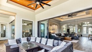 A spacious living area with a large sectional sofa, a glass-top coffee table, and wicker furniture. - Luxurious Vacation Retreat with Direct Gulf Access NEW! (Fort Myers)