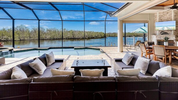 A spacious outdoor area with a pool, seating, and a view of a body of water. - Luxurious Vacation Retreat with Direct Gulf Access NEW! (Fort Myers)