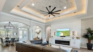 A spacious living room with a large sectional sofa, a fireplace, and a television mounted on the wall. - Luxurious Vacation Retreat with Direct Gulf Access NEW! (Fort Myers)