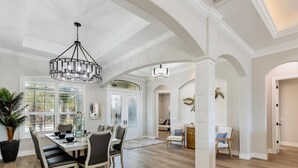 A spacious dining area with a high ceiling and natural light from large windows. - Luxurious Vacation Retreat with Direct Gulf Access NEW! (Fort Myers)